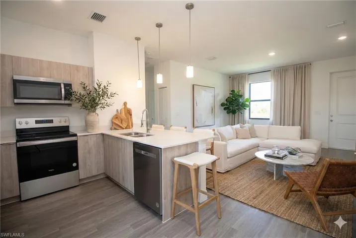 Kitchen with appliances with stainless steel finishes, pendant lighting, a peninsula, a kitchen breakfast bar, and modern cabinets  **photo has been virtually staged