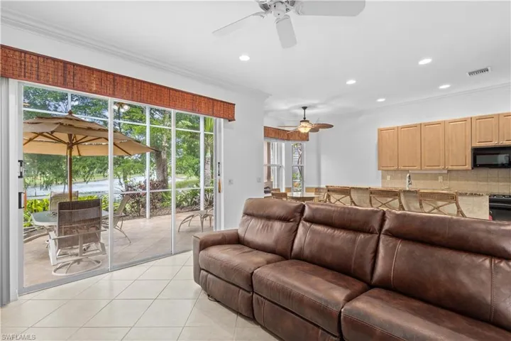 Kitchen with a ceiling fan, crown molding, light stone countertops, light tile patterned flooring, and black dishwasher