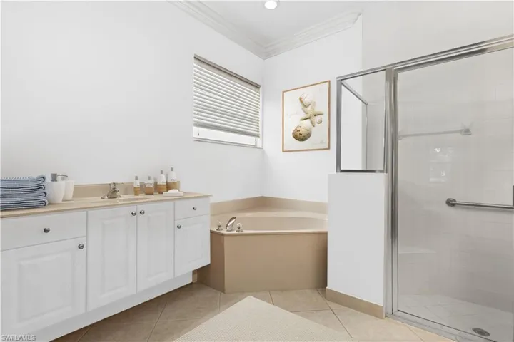 Ensuite bathroom with crown molding, vanity, and light tile patterned floors