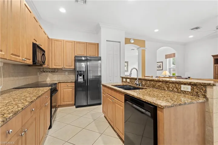 Kitchen featuring crown molding, backsplash, white cabinetry, a breakfast bar area, and a kitchen island with sink