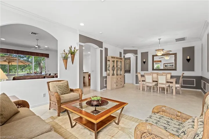 Living area with crown molding, arched walkways, light tile patterned flooring, a ceiling fan, and recessed lighting