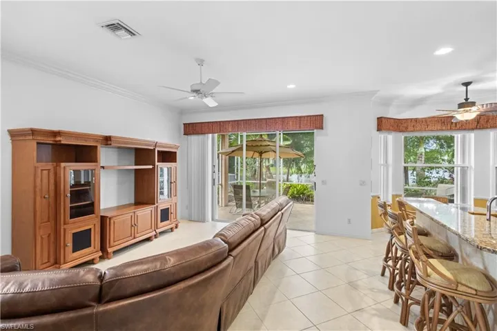 Kitchen featuring black appliances, ornamental molding, a kitchen island with sink, white cabinets, and tasteful backsplash