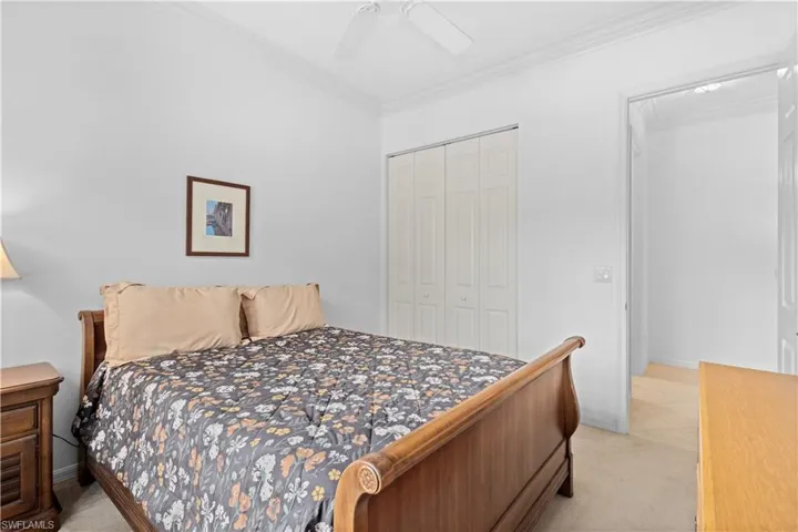 Bedroom featuring light colored carpet, crown molding, and a ceiling fan