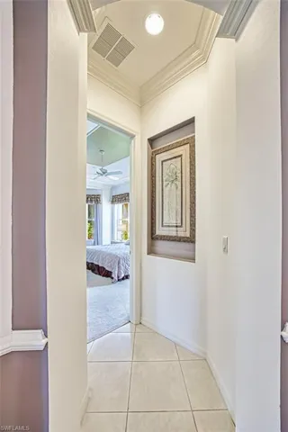 Hall featuring ornamental molding and light tile patterned flooring