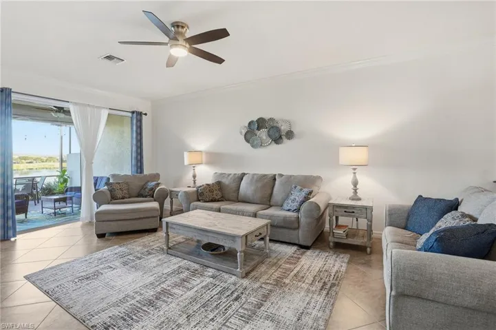 Living area with a water view, ornamental molding, ceiling fan, and light tile patterned floors
