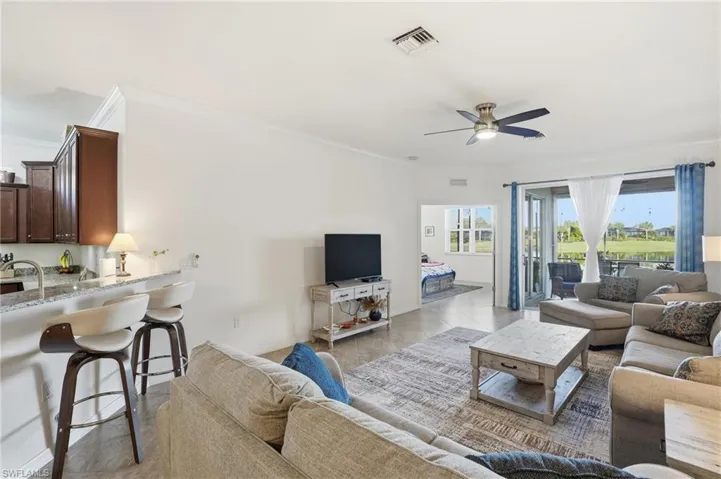 Living area featuring ornamental molding, ceiling fan, and light tile patterned floors