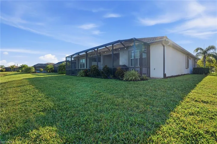 View of side of home with a sunroom, a lawn, a lanai, and stucco siding