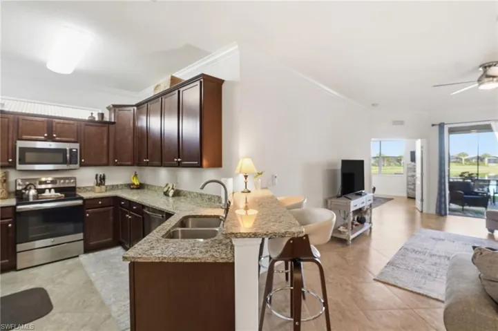 Kitchen with open floor plan, a kitchen bar, stainless steel appliances, a peninsula, and ornamental molding