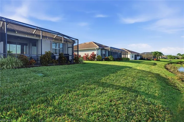 View of grassy yard with a sunroom and glass enclosure