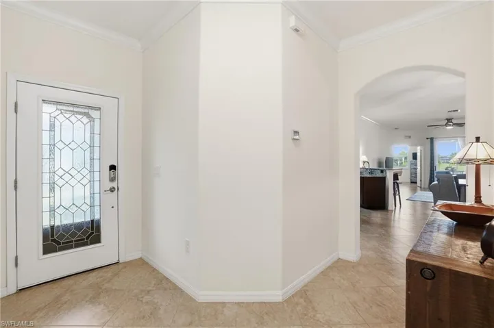 Entrance foyer featuring ornamental molding, a ceiling fan, and arched walkways