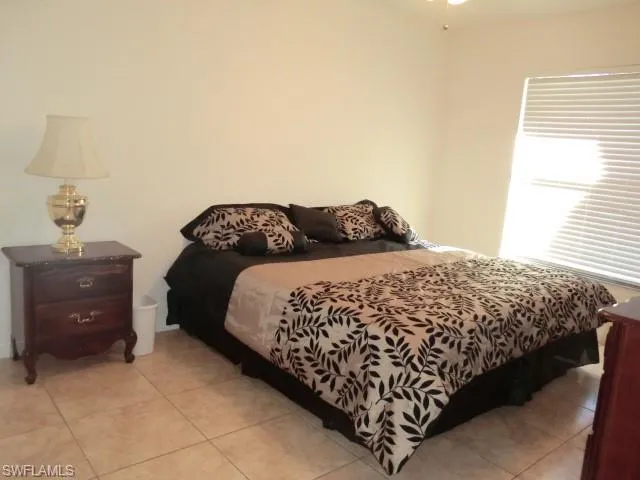 Neutral tone wall paint, tile flooring, window with horizontal blinds, and a ceiling fan with light fixture