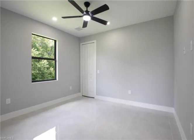 Tiled spare room featuring ceiling fan