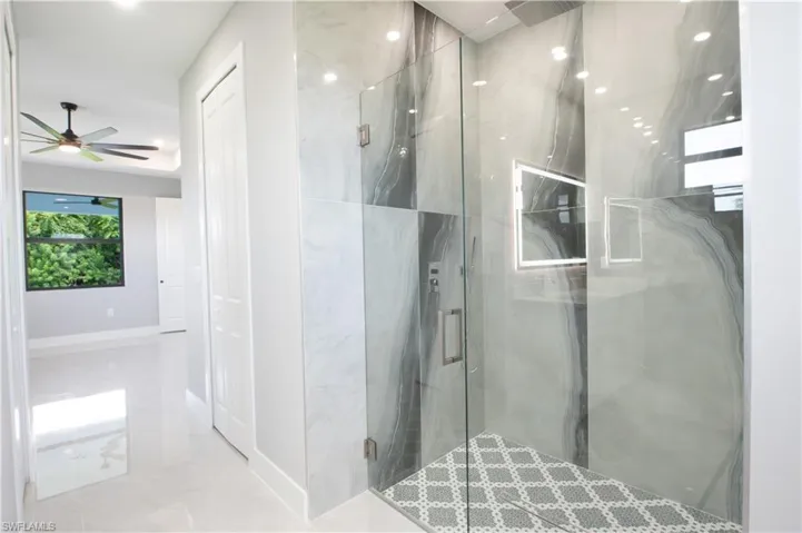 Bathroom featuring a shower with shower door and ceiling fan