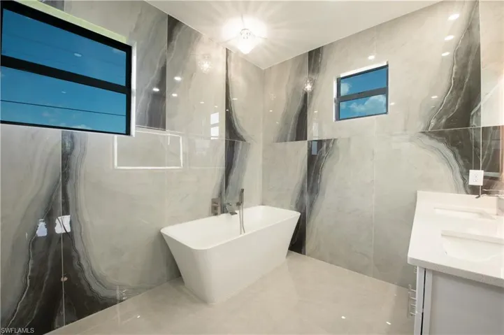 Bathroom featuring vanity, tile walls, and a washtub