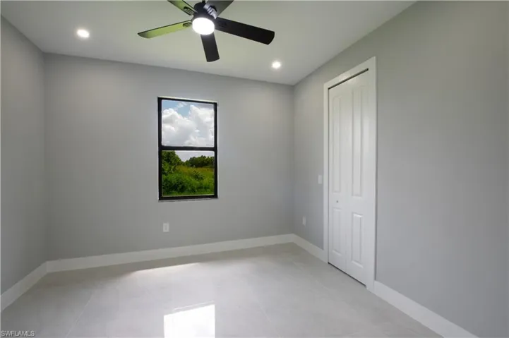 Unfurnished bedroom with light tile patterned floors, ceiling fan, and a closet