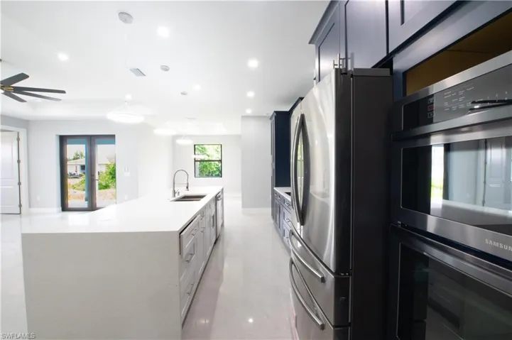 Kitchen with appliances with stainless steel finishes, a center island with sink, sink, and ceiling fan