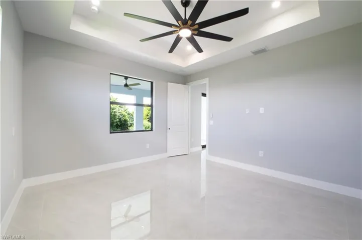 Spare room featuring a raised ceiling and ceiling fan