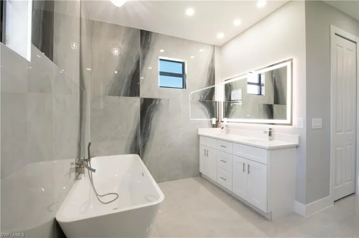 Bathroom with vanity, a wealth of natural light, and a bathing tub