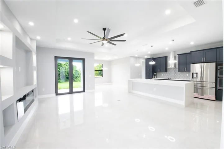 Unfurnished living room with a tray ceiling, sink, and ceiling fan