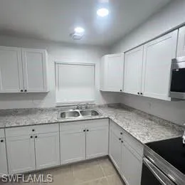 Kitchen featuring appliances with stainless steel finishes, light countertops, white cabinetry, and light tile patterned floors