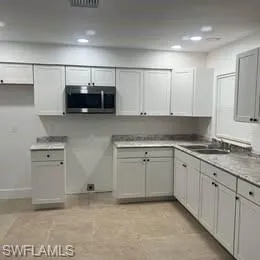Kitchen featuring recessed lighting, stainless steel microwave, gray cabinetry, and light countertops
