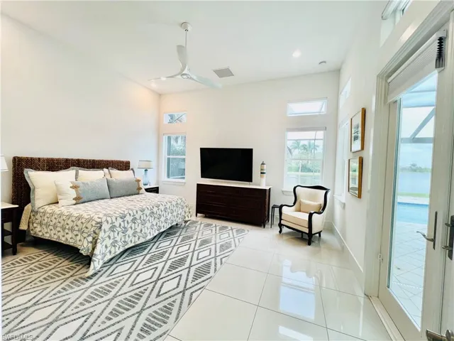 Bedroom featuring access to the lanai, natural light, electric blinds, lake views, and ceiling fan