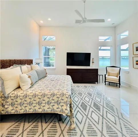 Bedroom featuring lakeside virews, light tile patterned floors, and ceiling fan