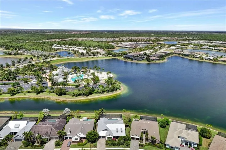 Aerial view featuring home (with white roof), lake and clubhouse