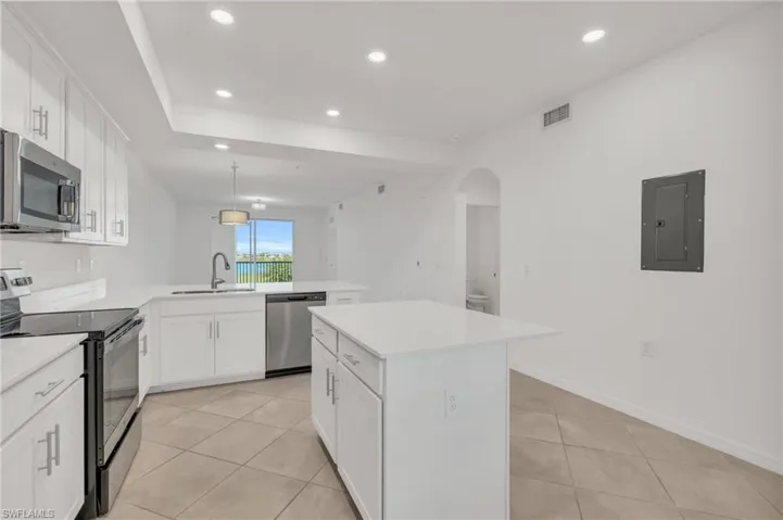 Kitchen with white cabinets, kitchen peninsula, stainless steel appliances, a center island, and electric panel