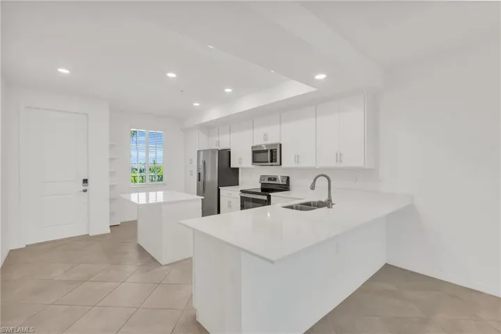 Kitchen featuring sink, white cabinets, kitchen peninsula, stainless steel appliances, and light tile patterned floors