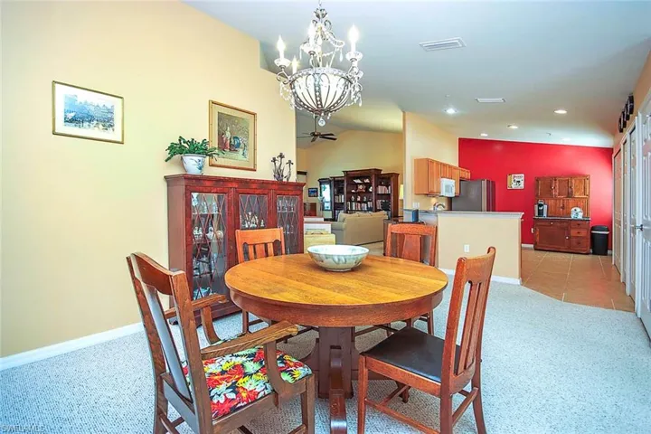 Dining area featuring light carpet, hanging lights, and vaulted ceiling