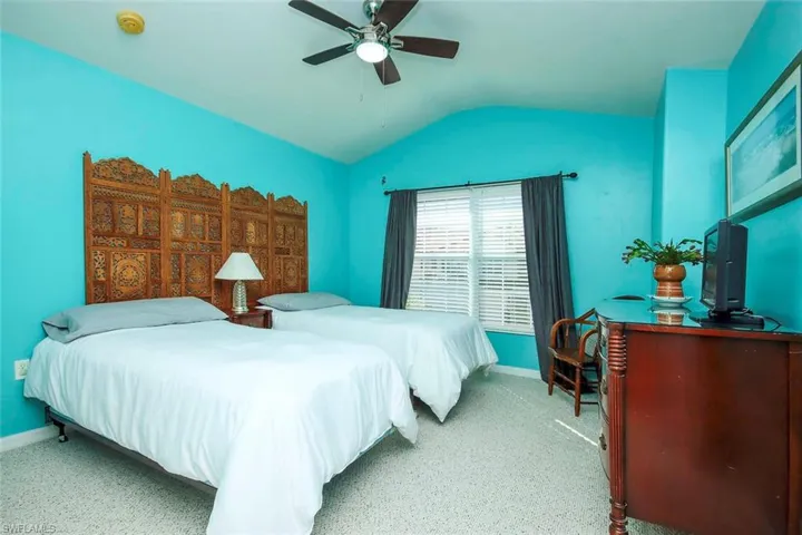 Carpeted bedroom with lofted ceiling and a ceiling fan