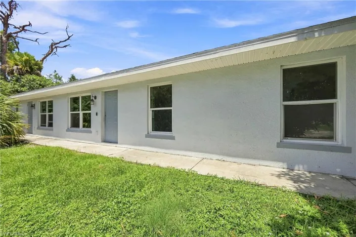Stucco exterior with multiple windows, each featuring a gray sill