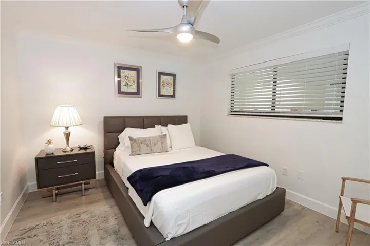 Bedroom with wood finished floors, ornamental molding, baseboards, and a ceiling fan