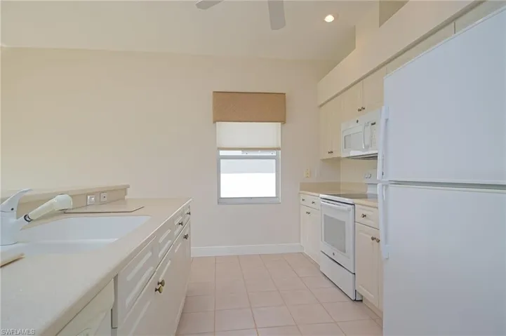 Kitchen with porcelain sink, white cabinetry, and white appliances
