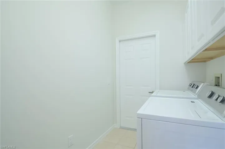 Laundry room featuring cabinets, light tile patterned flooring, and separate washer and dryer