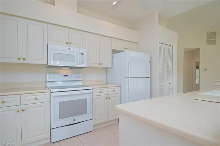 Kitchen with white cabinets, ceiling fan, light tile patterned floors, sink, and white appliances