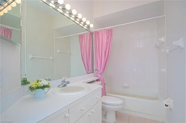 Full second bathroom featuring vanity, toilet, shower / bathtub combination with curtain, and tile patterned floors