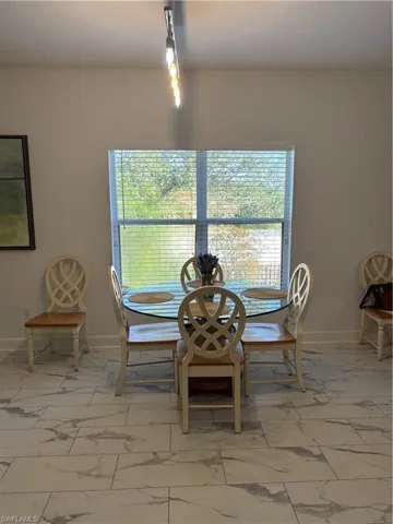 Dining space with light marble finish floors and baseboards