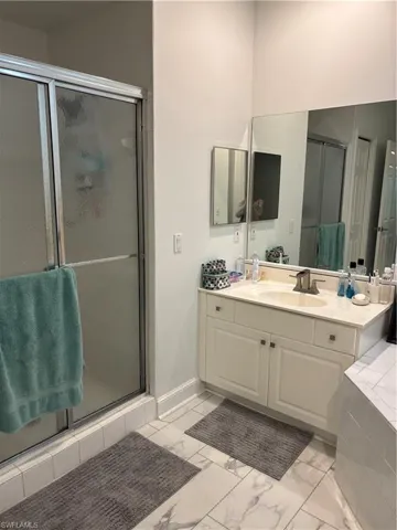 Bathroom featuring vanity, a stall shower, and light marble finish flooring