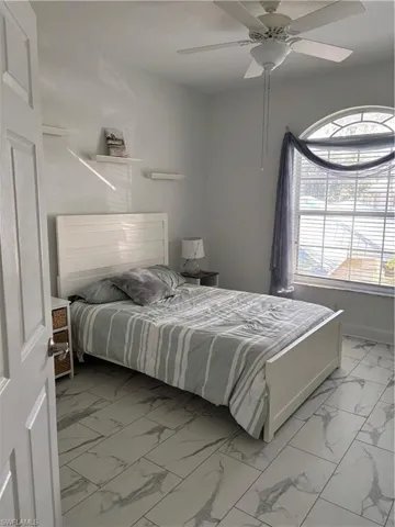 Bedroom with light marble finish floors and ceiling fan