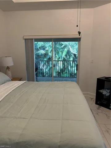 Bedroom featuring marble look tiles, access to exterior, and multiple windows