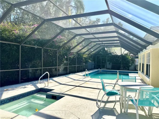 Outdoor pool featuring a sunroom, glass enclosure, an in-ground hot tub, and a patio