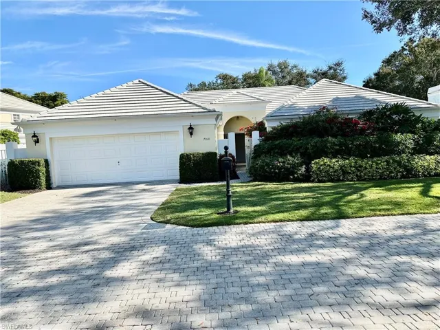 Ranch-style house featuring a tiled roof, decorative driveway, a front lawn, an attached garage, and stucco siding