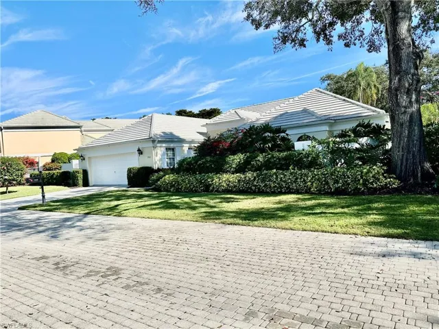 View of property exterior with a yard, a garage, driveway, a tile roof, and stucco siding