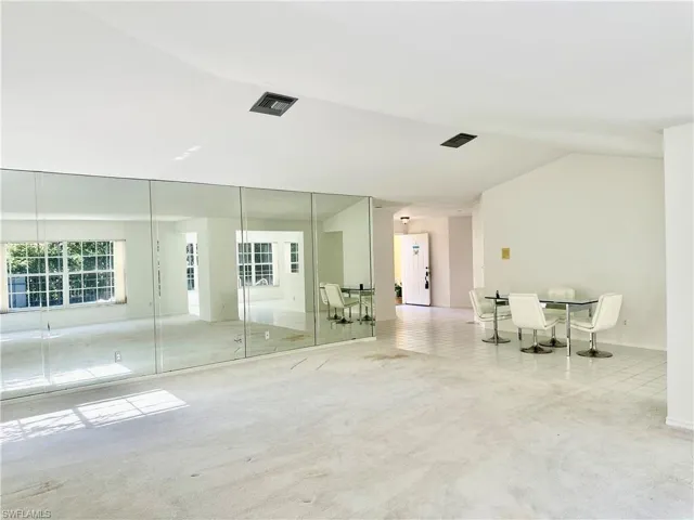 Unfurnished room featuring light carpet and vaulted ceiling