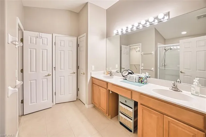 Full bath with a stall shower, a closet, light tile patterned flooring, and double vanity
