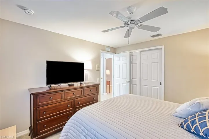 Bedroom with light carpet, a ceiling fan, and a closet