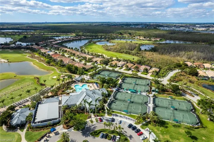 Aerial view of property and surrounding area with a golf club, a nearby body of water, and nearby suburban area