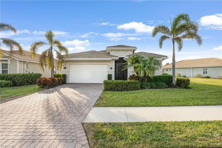 View of front of property with a garage, decorative driveway, a front yard, and stucco siding